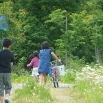 保養の様子。自転車を押す子ども、虫とり網をもつ子ども。