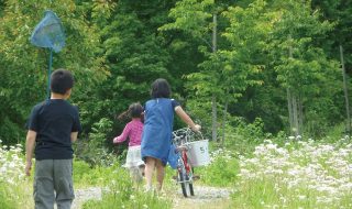 保養の様子。自転車を押す子ども、虫とり網をもつ子ども。