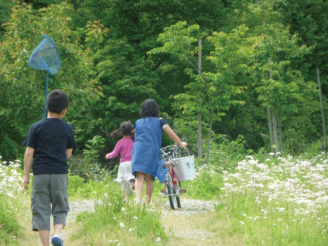 保養の様子。自転車を押す子ども、虫とり網をもつ子ども。