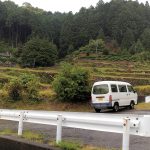 色川地区の風景。段々畑のある山都里に１台の車が停車している。