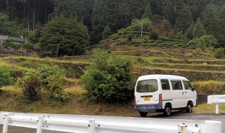 色川地区の風景。段々畑のある山都里に１台の車が停車している。