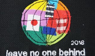 ミシンで刺繍された地球。日本のほかさまざまな国旗、色が組み合わさっている。