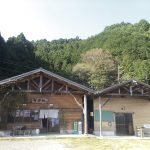 ２棟並んだ木造の建物。すぐうしろには山がせまっている