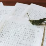 びっしり書かれた何枚もの原稿用紙。用紙の上に草でつくったバッタが置かれている